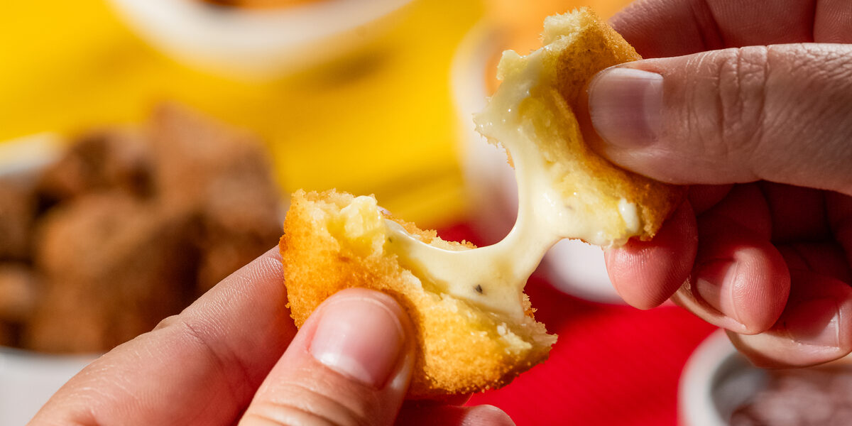 Salgado de queijo puxando ao ser partido ao meio