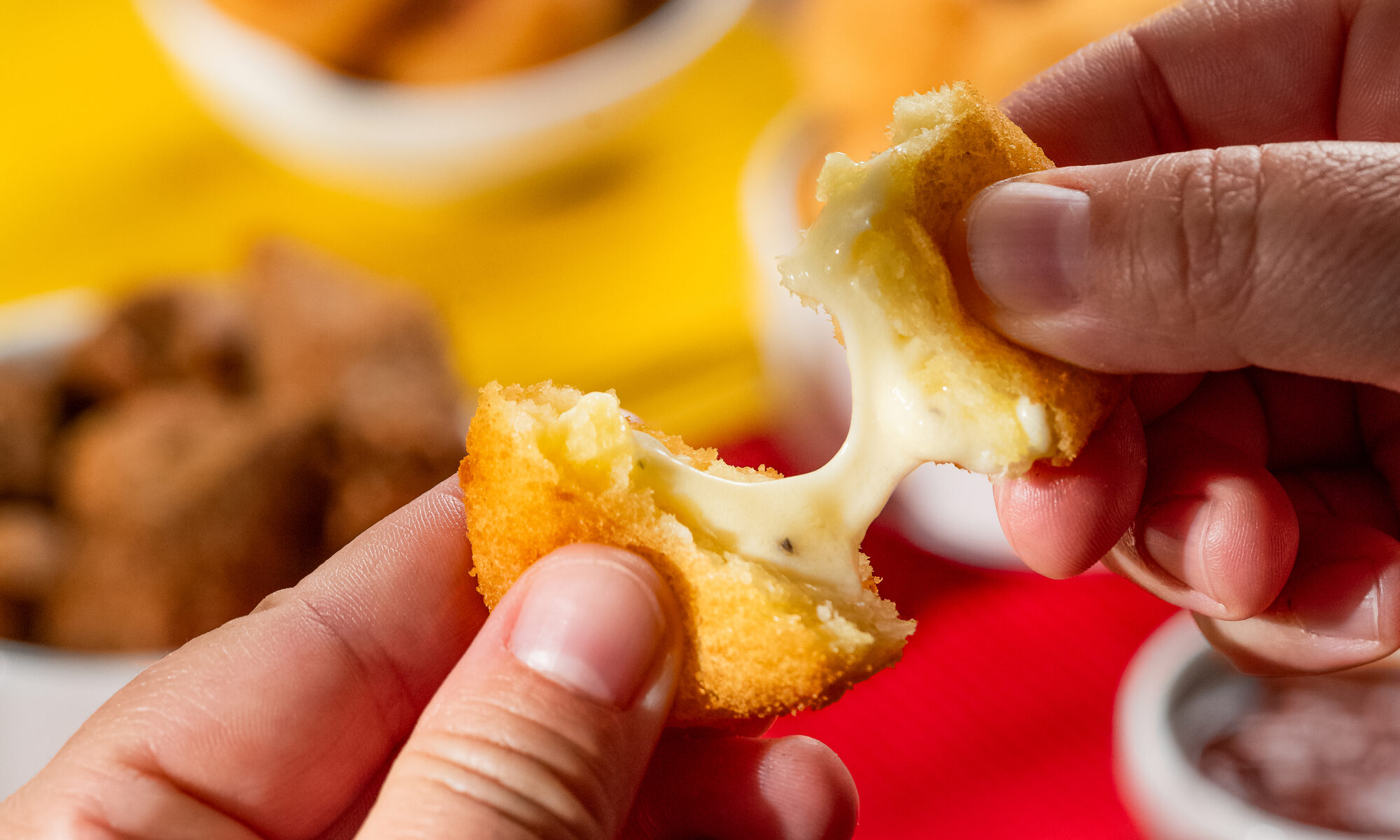 Cliente segurando uma bolinha de queijo B. foods