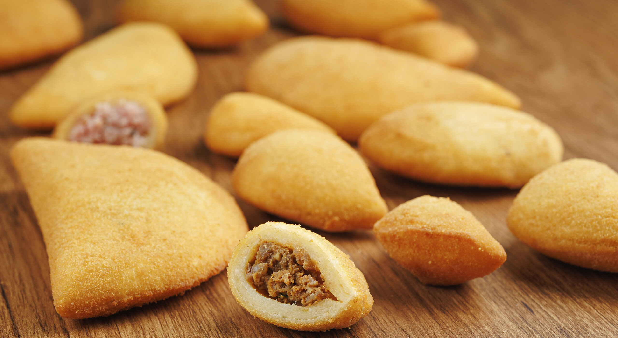 Salgados de massa de mandioca da B. foods sobre tábua de madeira